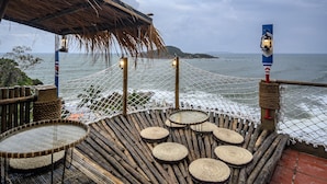 A wooden deck with woven mats and tables overlooking the sea. - Mira Bai Xep Quy Nhon - The Hidden Jewel - Hostel (Quy Nhon Nam)