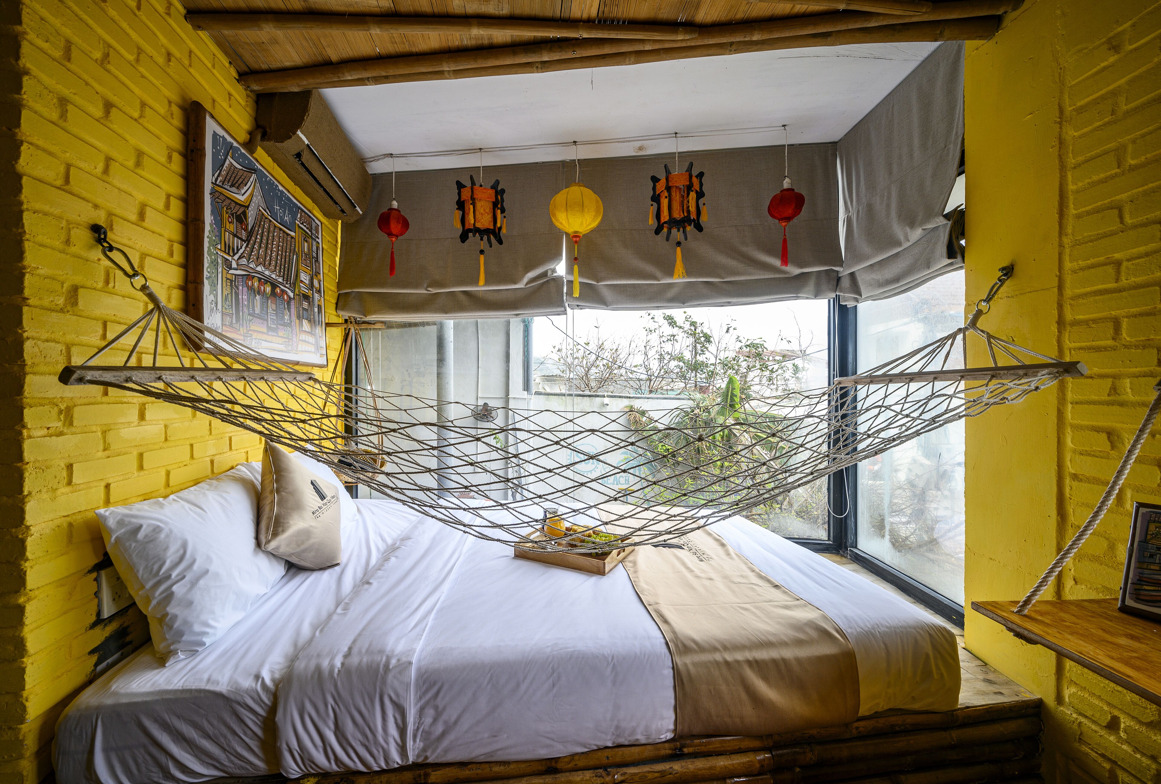 A bed with a hammock, a window with curtains, and a yellow brick wall.
