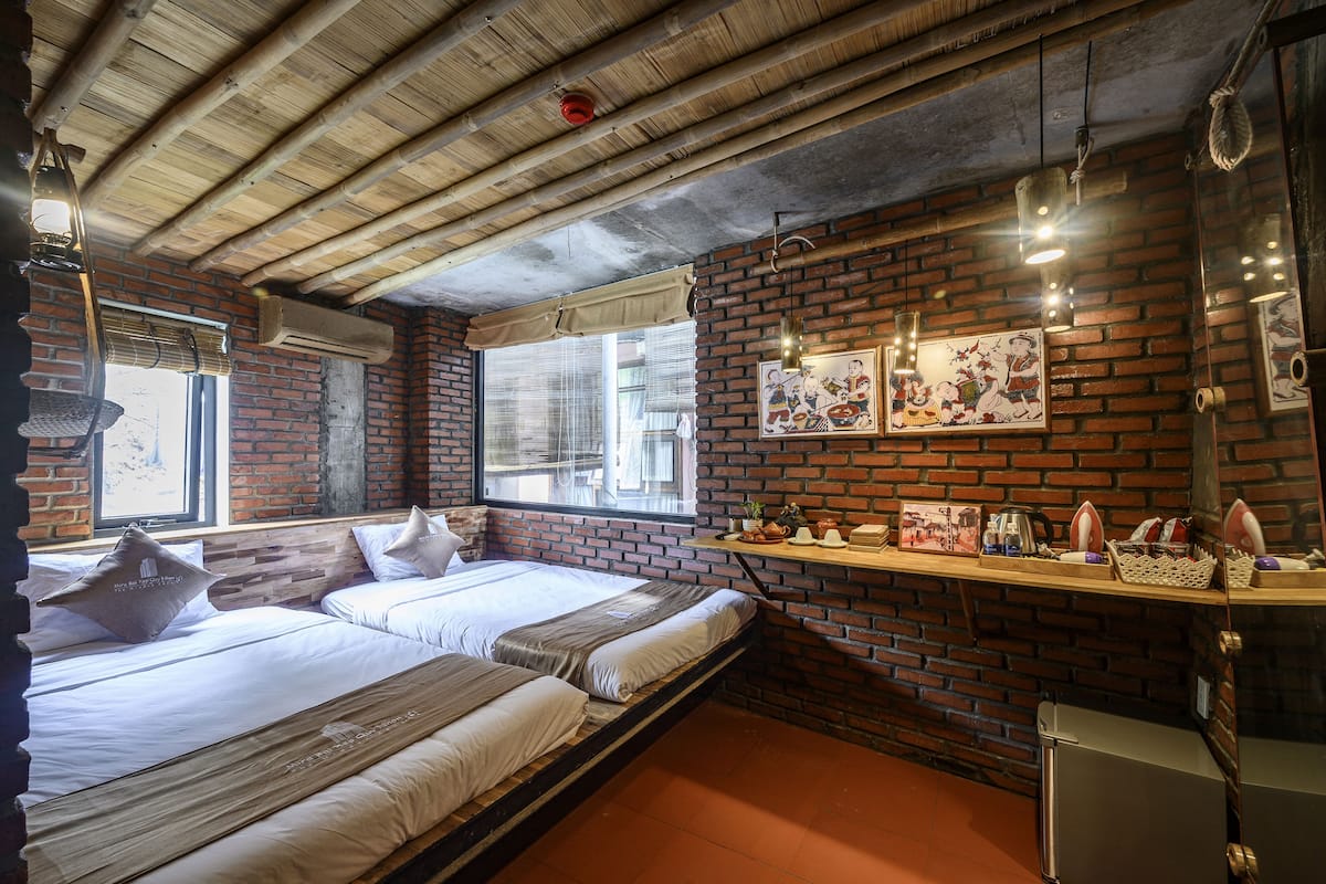 A room with a brick wall, wooden ceiling, and a bed with white bedding.
