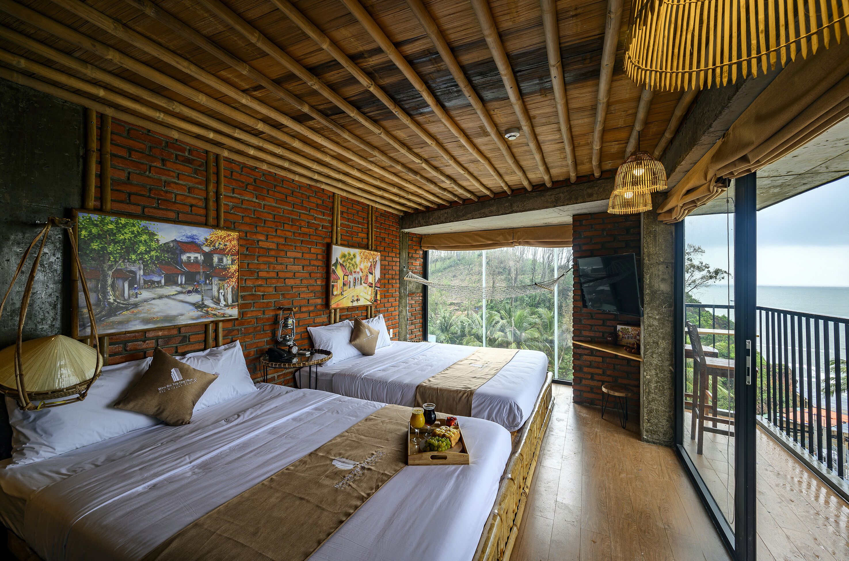 Quarto com duas camas, uma janela grande e varanda com vista.