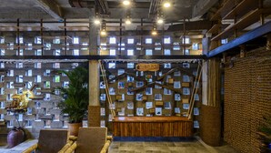 A spacious lobby with a high ceiling, exposed beams, and a wall of small windows. There are seating areas with wooden furniture and a central wooden bench. - Mira Bai Xep Quy Nhon - The Hidden Jewel - Hostel (Quy Nhon Nam)