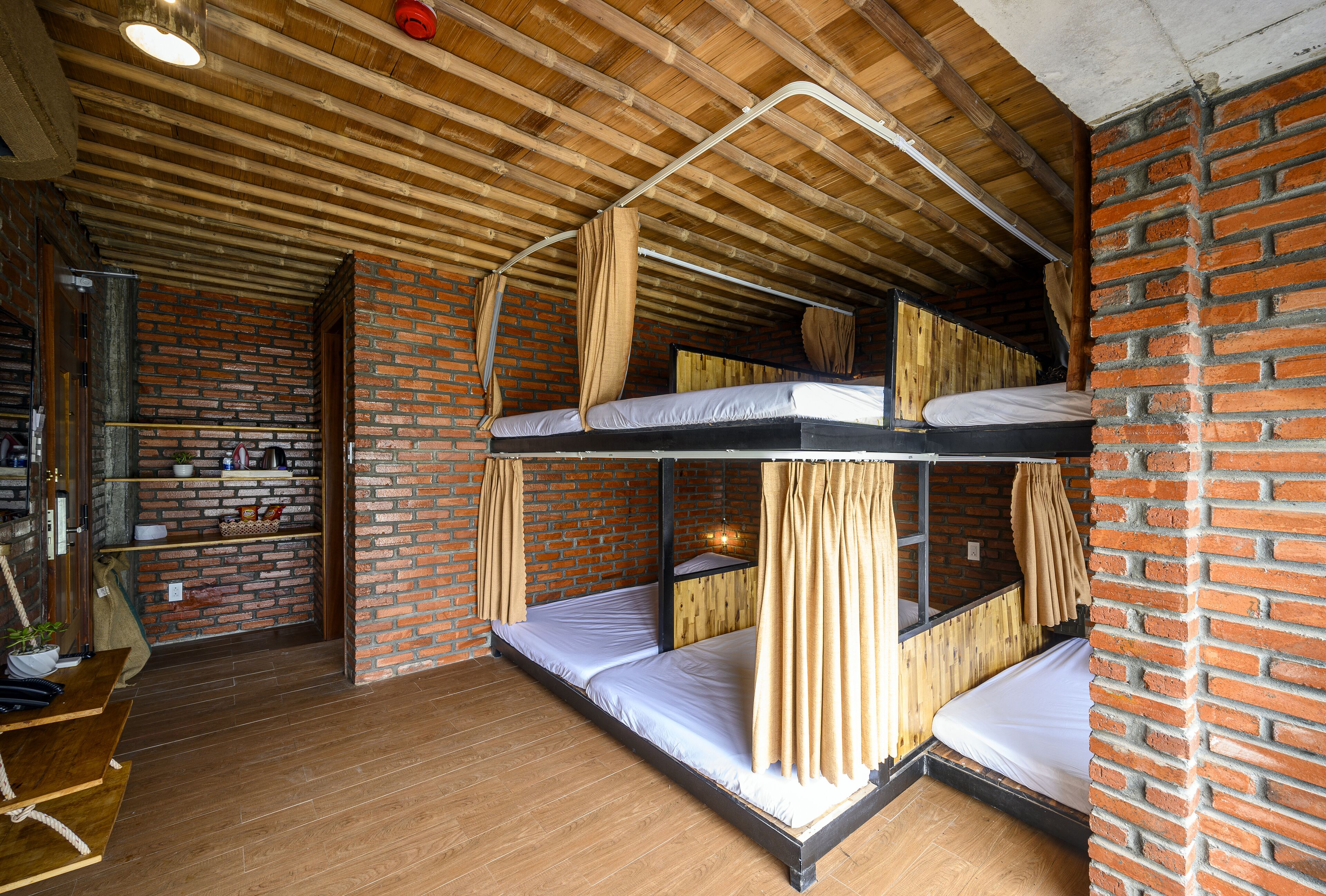 A bunk bed room with wooden beams and brick walls.