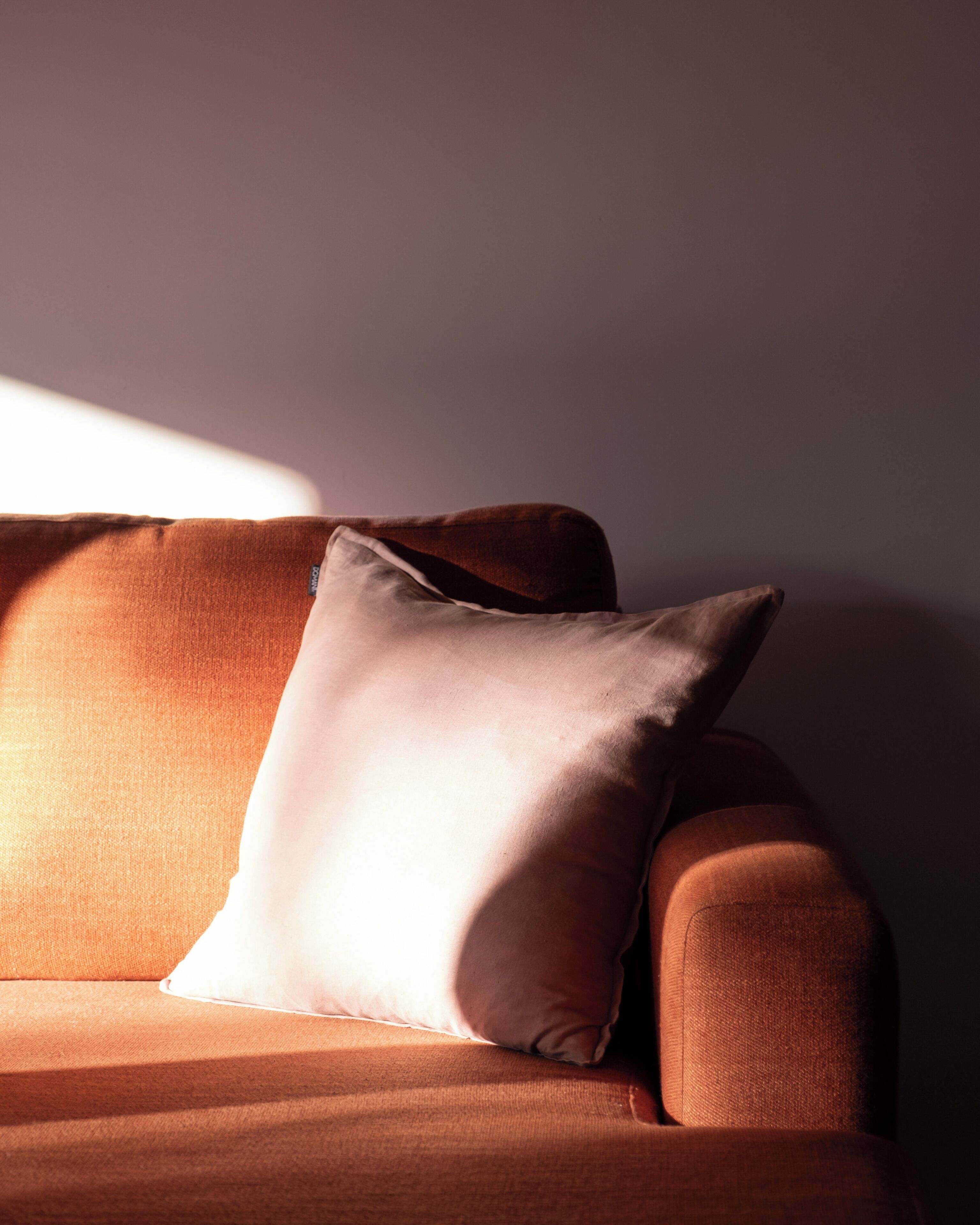En brun soffa med en ljusfärgad kudde.