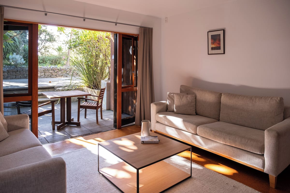 Una sala de estar moderna con un sofá, una mesa de centro y un comedor con mesa y sillas.