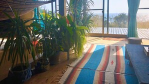 A room with a large window, a hammock, and several potted plants. - Galaxy Guest House (Hachijo)