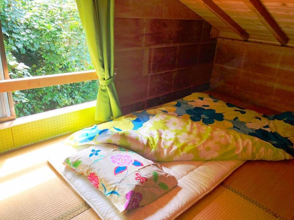 Una habitación acogedora con cama, ventana con cortinas y vistas a zonas verdes.