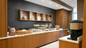 A breakfast buffet with various food items and a coffee machine.