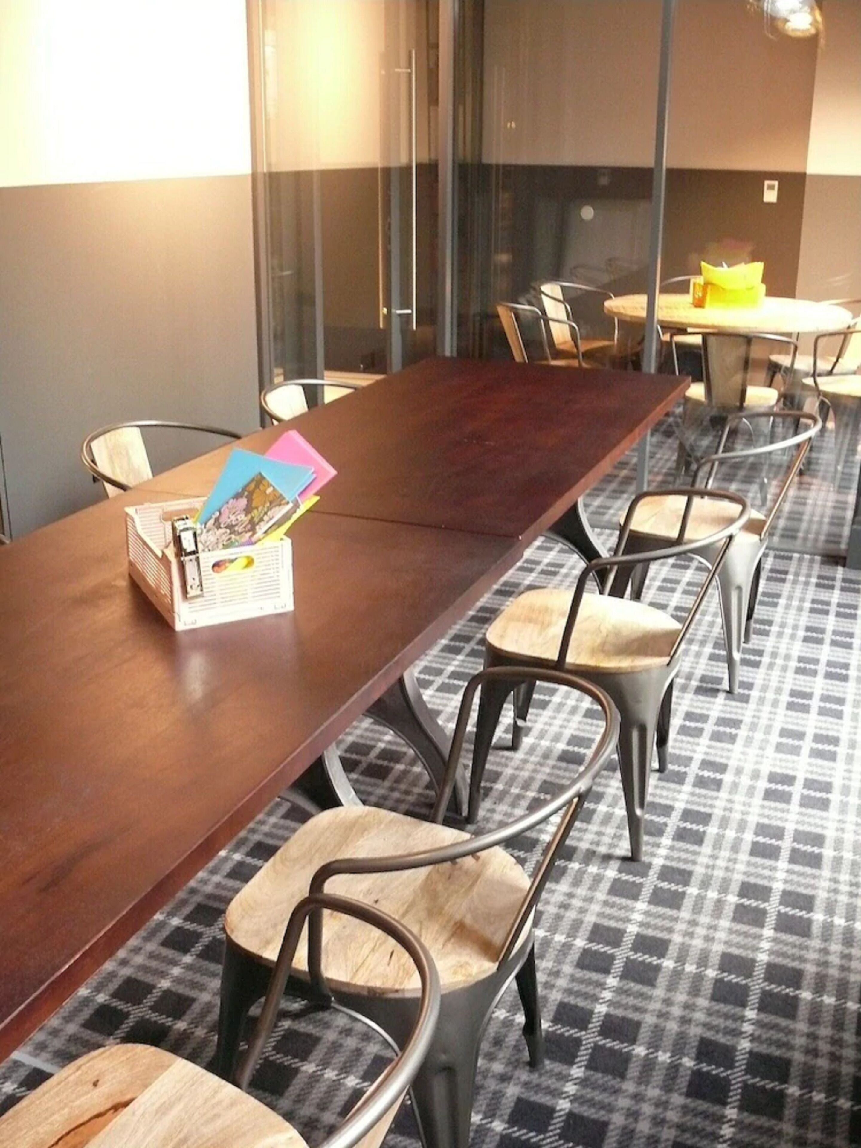 Uma sala de conferências com uma mesa comprida e cadeiras, uma divisória de vidro e um tapete estampado.