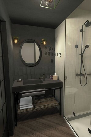Un baño moderno con piso de madera oscura, un espejo redondo, encimera negra y cabina de ducha con vidrio.