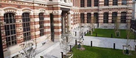 Un edificio grande e histórico con un patio que tiene césped y árboles.