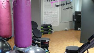 Un gimnasio con equipo de ejercicio, incluyendo sacos de boxeo y balones medicinales.