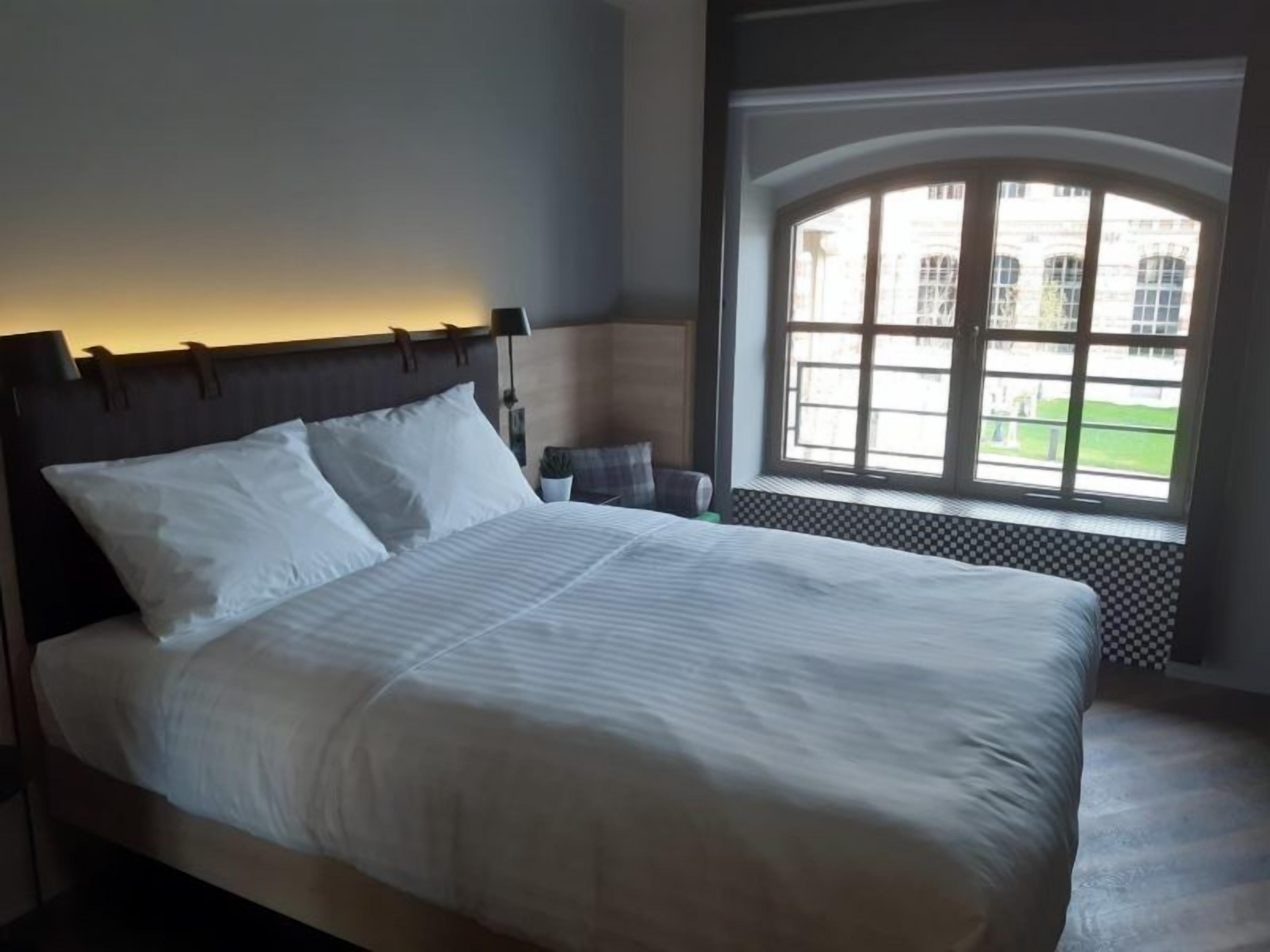 A neatly made bed with white linens in a hotel room.