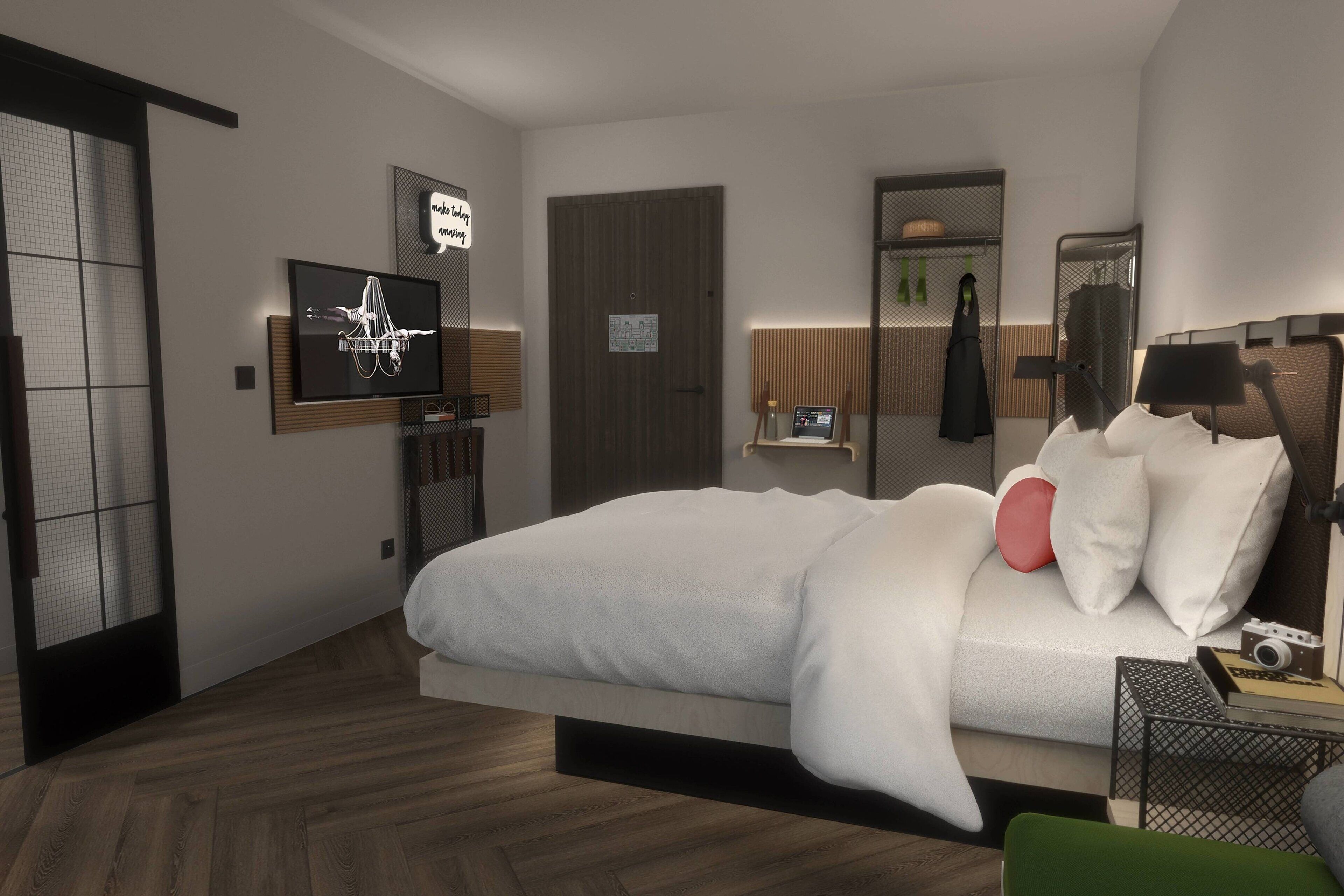 Ein modernes Hotelzimmer mit Bett, Fernseher, Spiegel und einem kleinen Tisch mit einer Kamera.