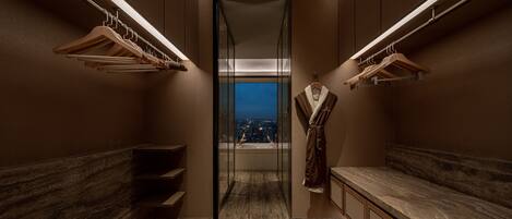 A modern hotel bathroom with wooden floors, marble countertops, and a view of the city at night.