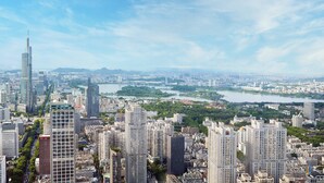 A cityscape with high-rise buildings, a river, and a distant mountain range.