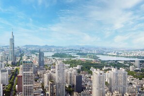 A cityscape with high-rise buildings, a river, and a distant mountain range.