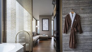 A modern bathroom with a large mirror, a bathtub, and a wooden floor.