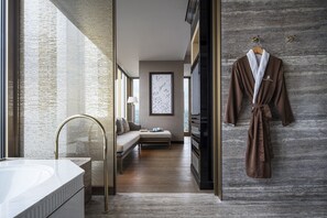 A modern bathroom with a large mirror, a bathtub, and a wooden floor.