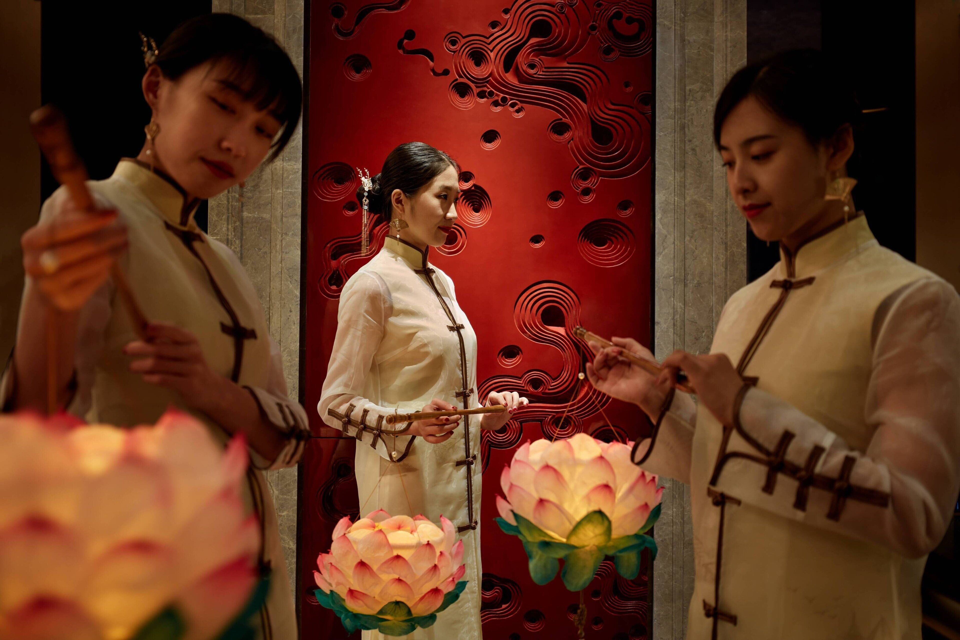 Three individuals in traditional attire playing stringed instruments.
