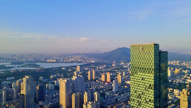 A high-rise hotel with a distinctive green facade and the name "The Ritz-Carlton" on the top.