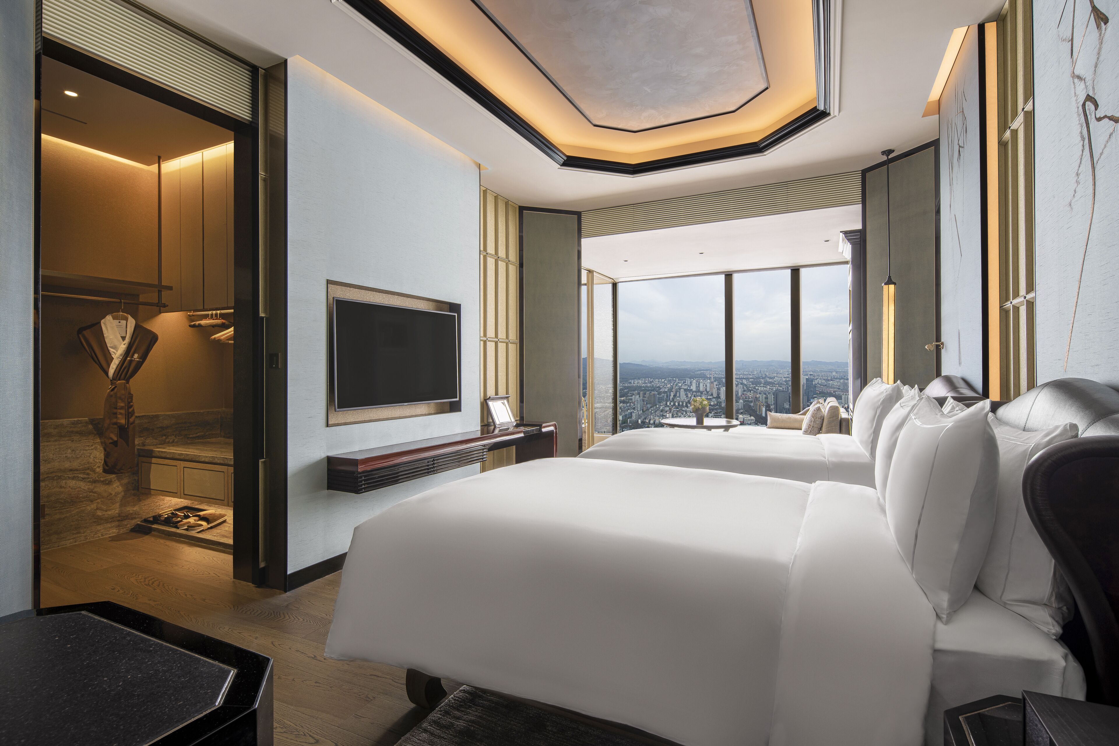 A modern hotel room with a large bed, a TV, and a city view.