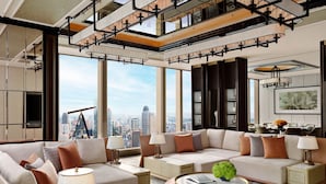 Un vaste espace de vie comprenant un grand canapé, de nombreuses lampes et une vue sur le paysage urbain grâce à de grandes fenêtres.
