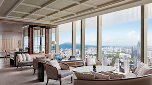 Un salon spacieux offrant une vue sur la ville, doté de grandes fenêtres et meublé avec des éléments de design moderne.