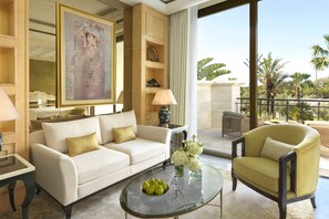 A well-appointed living room with a sofa, armchairs, a glass coffee table, and a large painting.