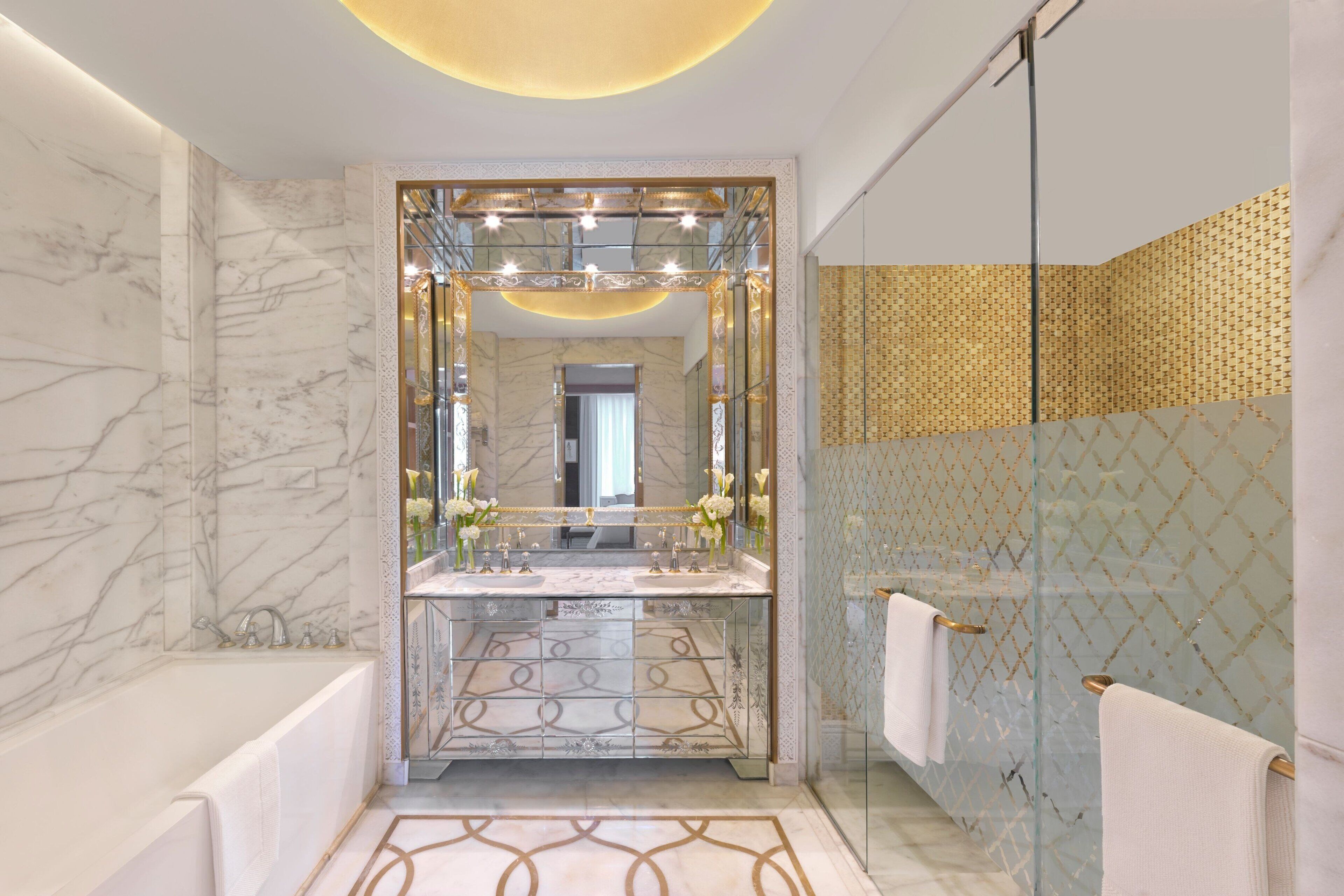 A modern bathroom with a marble vanity, a glass shower enclosure, and a patterned tile backsplash.