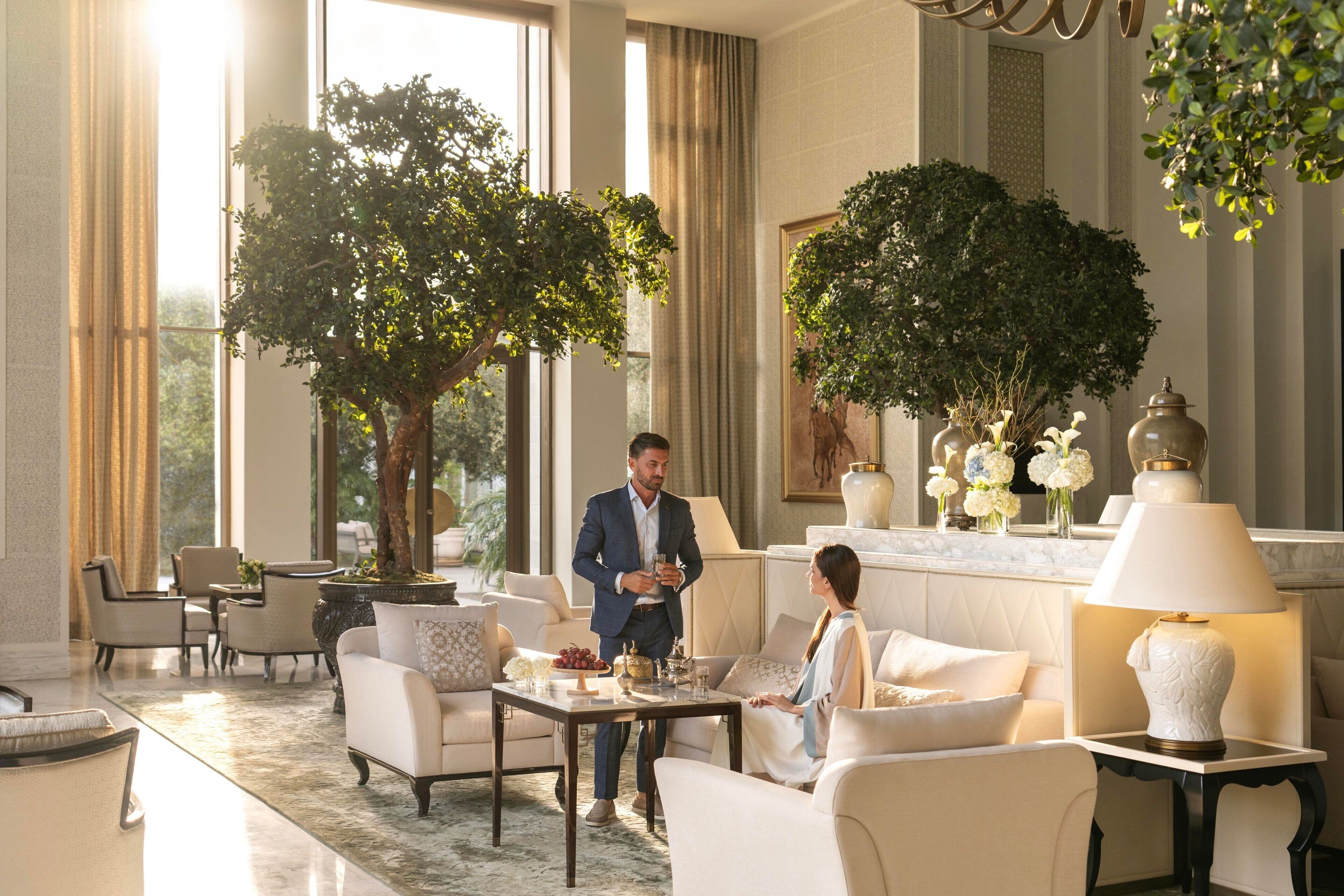 A spacious lobby with a large tree, comfortable seating, and a well-lit area with a lamp.
