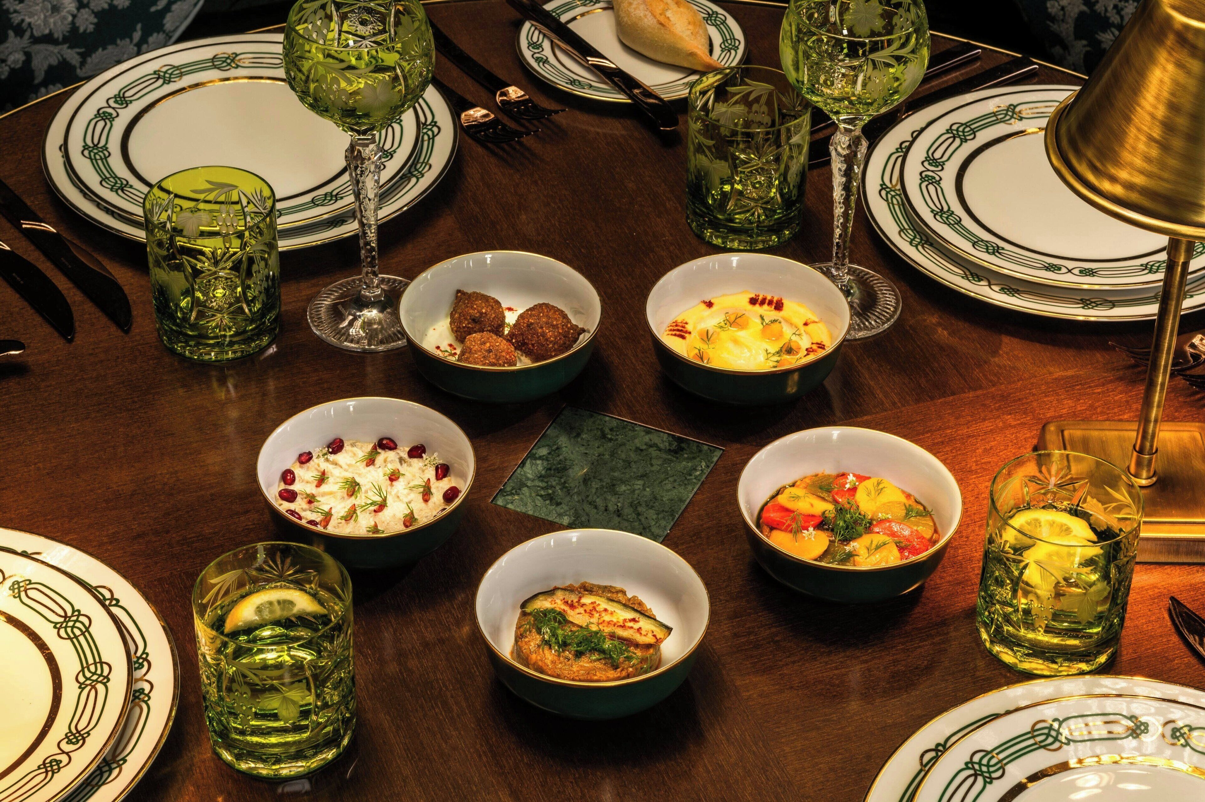 Una mesa de comedor dispuesta con diferentes platos, vasos y cubiertos.