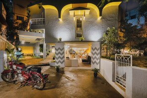 A modern building with a central entrance, a reception desk, and a motorcycle parked outside. - Zostel Bangalore - Hostel (Bengaluru)