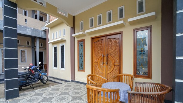 A courtyard with a motorcycle, wooden chairs, and a table.