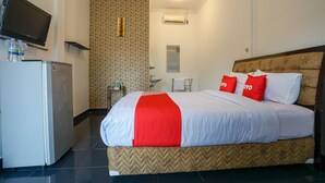 A hotel room with a bed, a television, a refrigerator, and a bathroom.