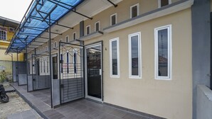A building with a covered entrance, multiple windows, and a tiled floor.