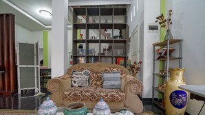 A living room with a patterned sofa, a glass coffee table, and decorative vases.