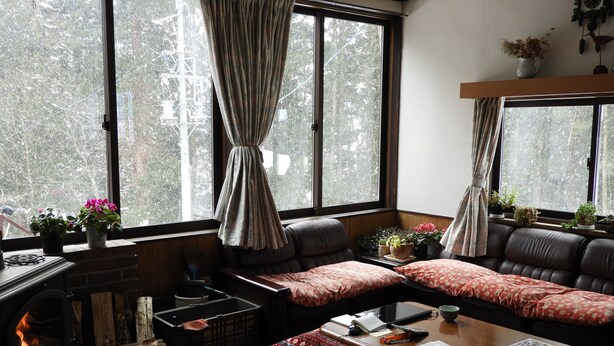 Una sala de estar acogedora con chimenea, sofá de cuero y ventanas grandes con cortinas.