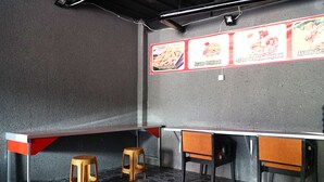 L’intérieur d’un restaurant avec un comptoir, des tabourets et des panneaux affichant le menu.