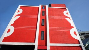 Un bâtiment rouge doté d’une fenêtre verticale centrale et d’éléments de design symétriques.