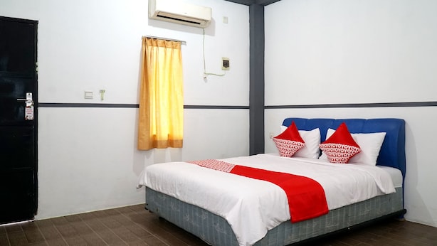 Une chambre d’hôtel avec un lit, une fenêtre avec un rideau, un appareil de climatisation et une porte.