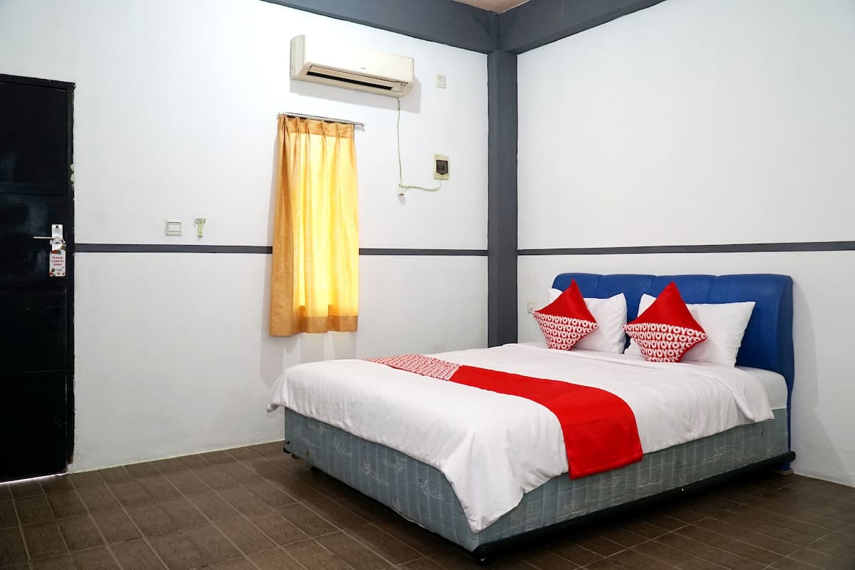 Een hotelkamer met een bed, een raam met gordijn, een airconditioning en een deur.