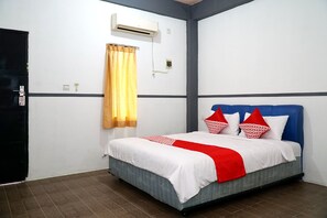 Ein Hotelzimmer mit Bett, Fenster mit Vorhang, Klimaanlage und Tür.