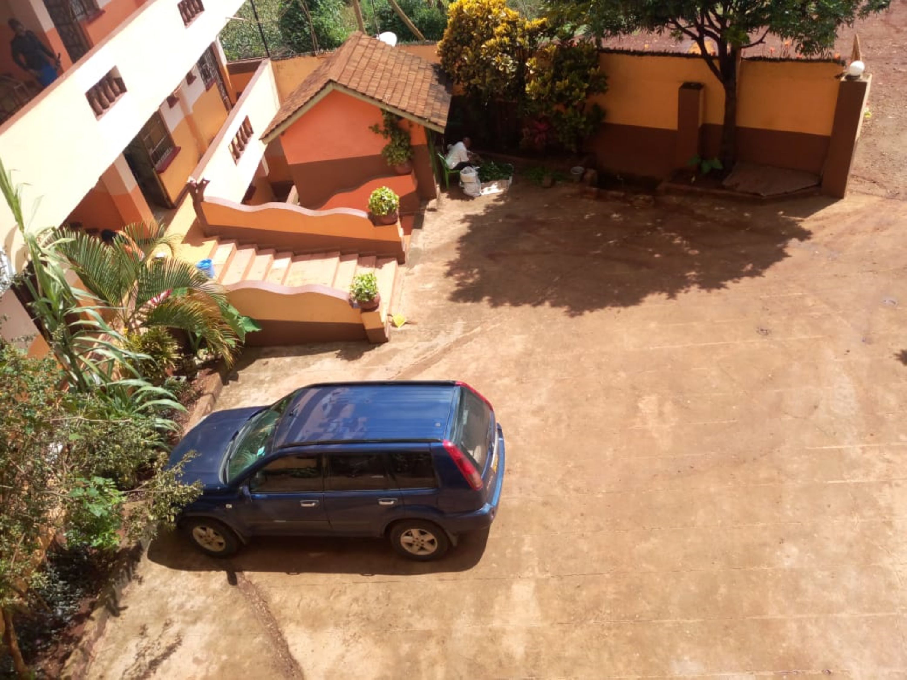 A blue car parked in a driveway with a house in the background.