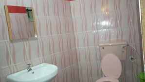 Un baño con baldosas a rayas, un lavamanos blanco y un inodoro rosa.
