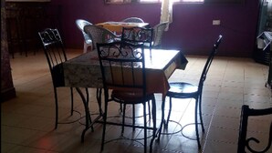 Un comedor con una mesa dispuesta para dos personas, sillas y una mesita de centro con una taza y un platillo.