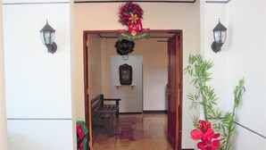 A hallway with a bench, a door, and a wall-mounted sign. - Linde's Inn Coron (Coron)