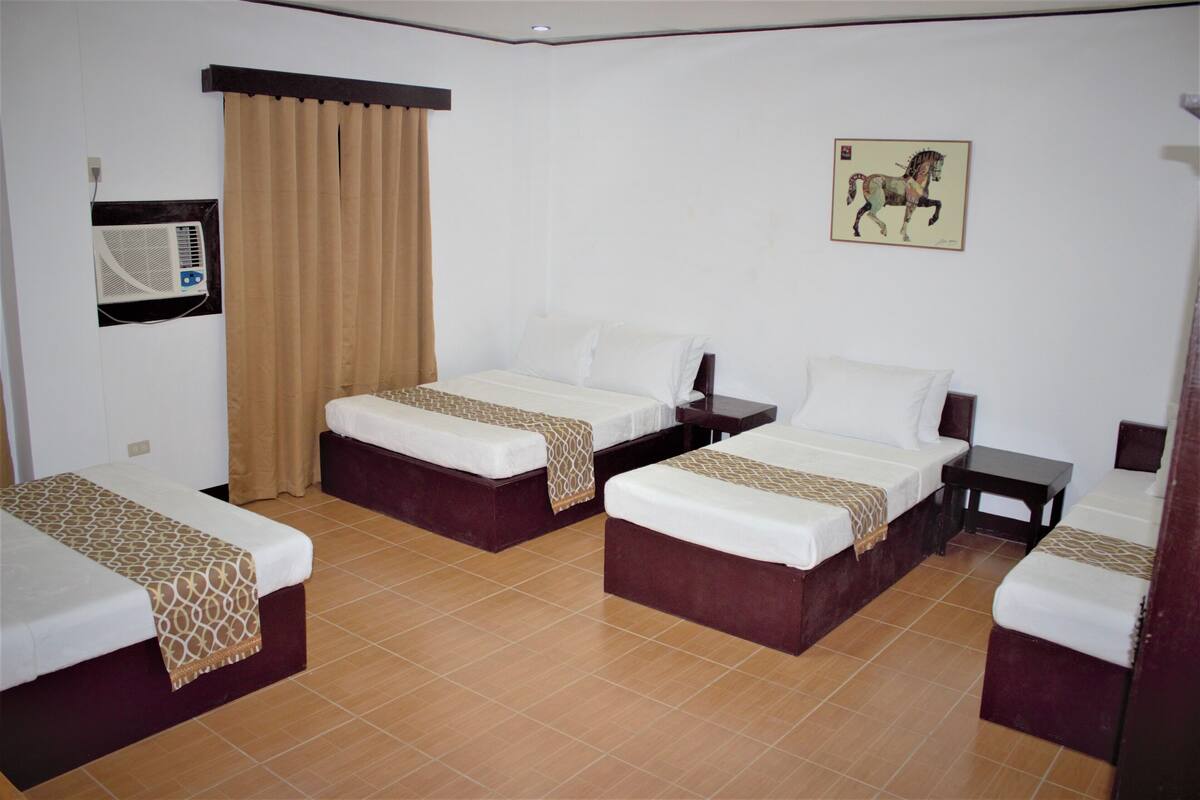 A hotel room with three beds, a wall-mounted air conditioner, a curtain, and a framed picture.