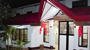 A building entrance with a red roof, white walls, and a wooden door. - Linde's Inn Coron (Coron)