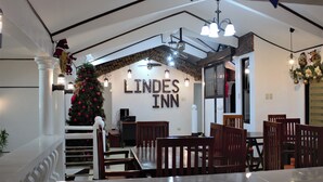A dining area with a Christmas tree, wooden chairs, and a sign that reads "LINDES INN". - Linde's Inn Coron (Coron)