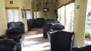 A waiting area with leather chairs, a television on the wall, and a patterned ceiling. - Salkan Hotel (Embu)